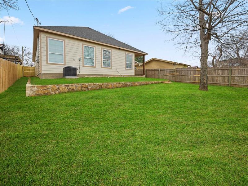 Rear view of house with a fenced backyard and a shingled roof