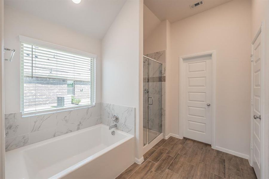 Full bath with a shower stall, a bath, wood finish floors, lofted ceiling, and recessed lighting Full bath with a shower stall, a bath, wood finish floors, lofted ceiling, and recessed lighting