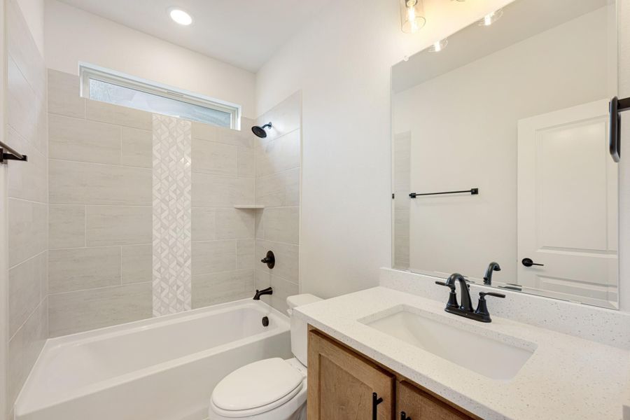 Bathroom with tiled tub-shower combo, white quartz vanity, wood cabinets, and black fixtures Bathroom with tiled tub-shower combo, white quartz vanity, wood cabinets, and black fixtures
