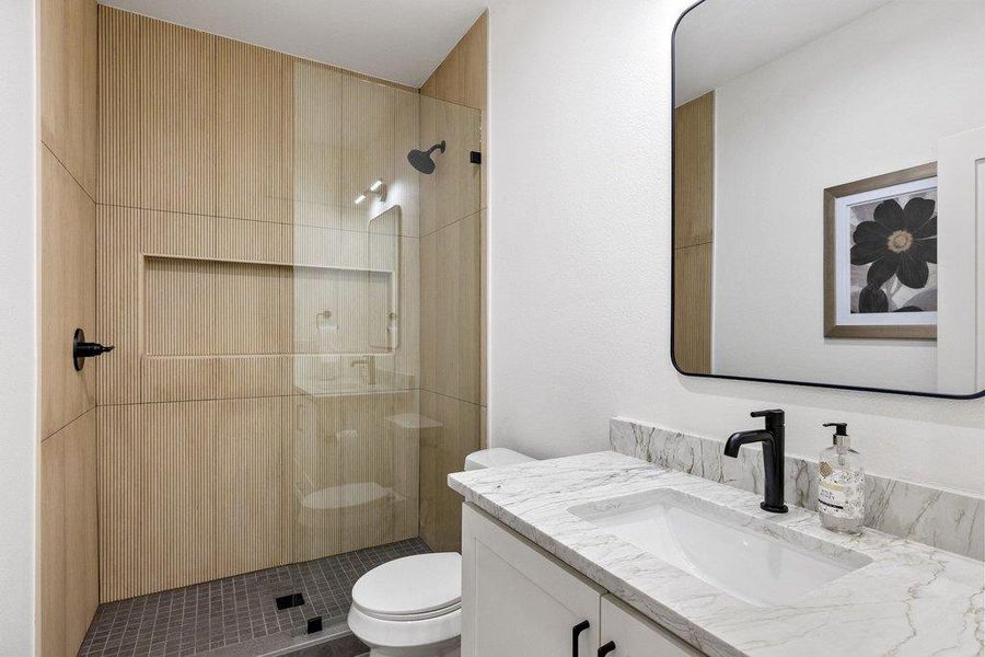 A well-appointed bathroom offers a modern vanity with a single sink and an enclosed shower featuring textured wood paneling. A well-appointed bathroom offers a modern vanity with a single sink and an enclosed shower featuring textured wood paneling.