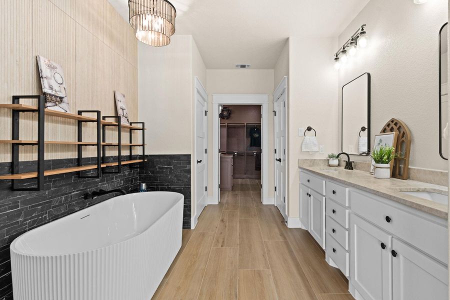 Full bath with a freestanding bath, wood finished floors, double vanity, a spacious closet, and a chandelier Full bath with a freestanding bath, wood finished floors, double vanity, a spacious closet, and a chandelier