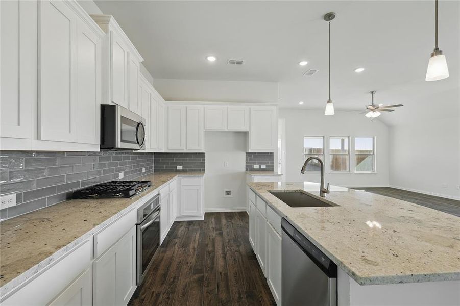 Kitchen with a kitchen island with sink, white cabinets, light stone countertops, ceiling fan, and dark wood-type flooring