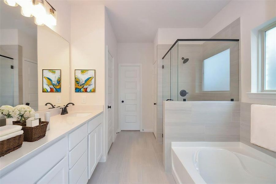 The primary bath provides a luxurious retreat, complete with a dual-sink vanity, modern lighting, and a walk-in glass-enclosed shower. The pristine tile flooring and neutral color palette enhance the room’s sophisticated ambiance.