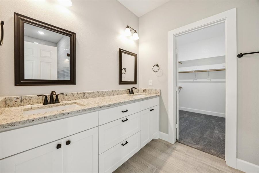 Bathroom featuring double vanity, wood finished floors, and a walk in closet Bathroom featuring double vanity, wood finished floors, and a walk in closet