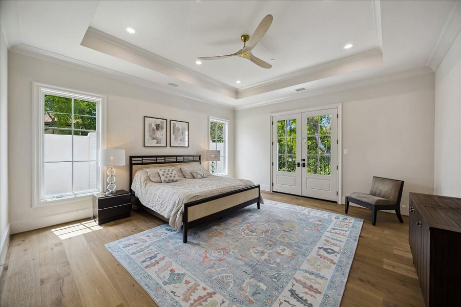 The primary suite offers a serene retreat with beautiful French white oak wide plank flooring, soaring ceilings with a tray detail, and crown molding. Divided light French doors open to the backyard and wooded ravine, bringing in natural light and creating a peaceful indoor-outdoor connection.  The spacious layout allows for many decorating/furnishing options!