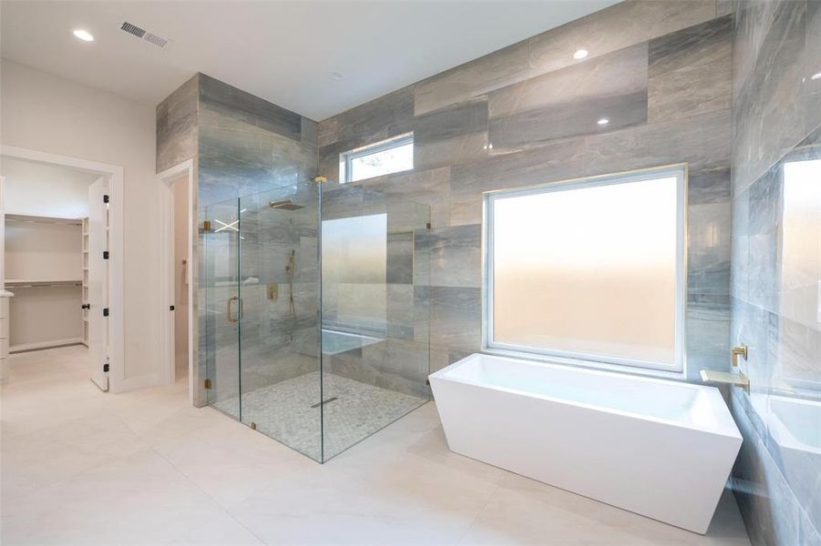 Bathroom with tile floors, shower with separate bathtub, and tile walls Bathroom with tile floors, shower with separate bathtub, and tile walls