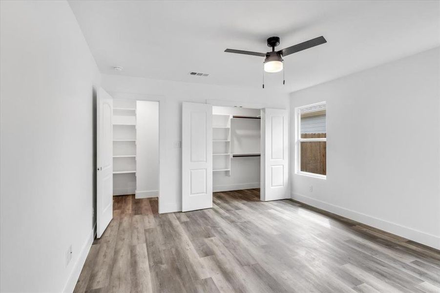 Unfurnished bedroom with light hardwood / wood-style floors, a spacious closet, and ceiling fan