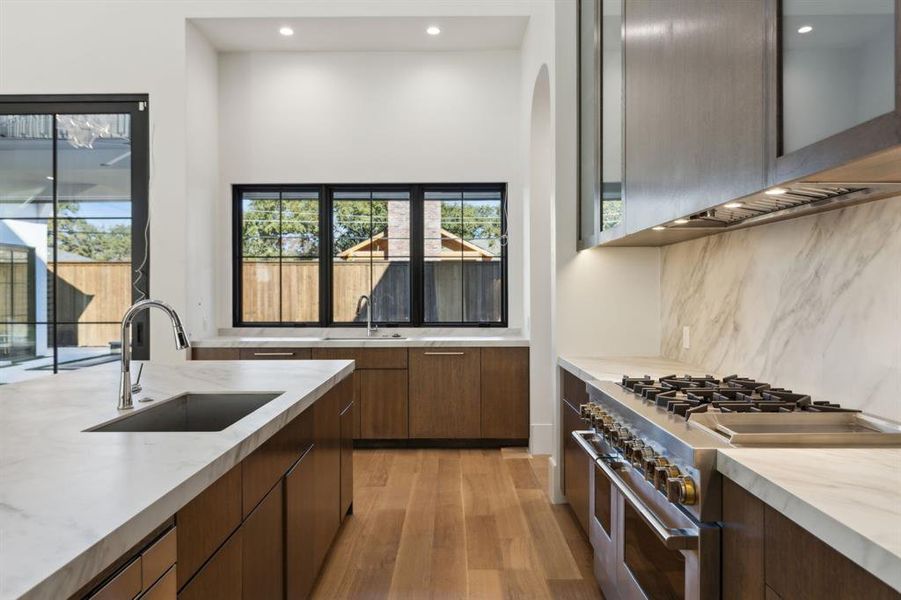 Kitchen featuring range with two ovens, light wood-style floors, modern cabinets, recessed lighting, and decorative backsplash