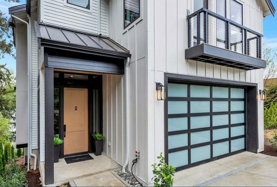 View of exterior entry featuring a standing seam roof, a garage, board and batten siding, and concrete driveway