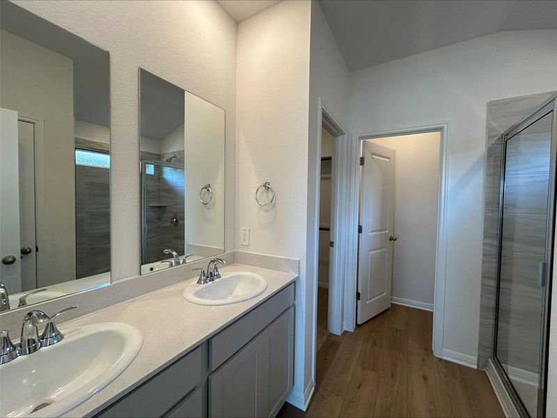 Bathroom featuring a shower stall, double vanity, and dark wood finished floors Bathroom featuring a shower stall, double vanity, and dark wood finished floors