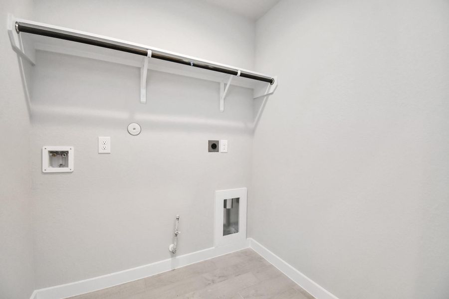 A perfect blend of functionality and comfort. Capture the essence of easy living with a first-floor laundry room, thoughtfully equipped with shelving for effortless organization. Both electric and gas connections available. Sample photo of completed home with similar floor plan. Actual colors and selections may vary.