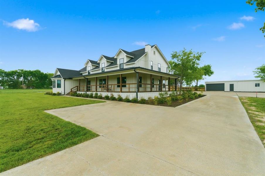 This property features a white exterior with a dark roof and multiple dormer windows, complemented by a wraparound porch with wood railings This property features a white exterior with a dark roof and multiple dormer windows, complemented by a wraparound porch with wood railings