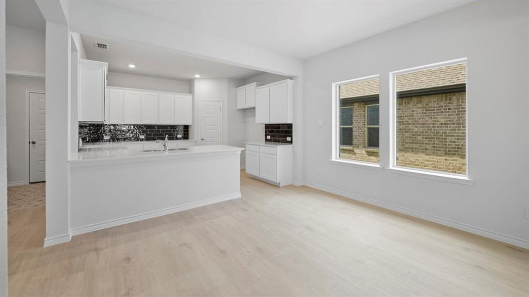Kitchen featuring white cabinetry, a peninsula, decorative backsplash, light wood-style flooring, and recessed lighting Kitchen featuring white cabinetry, a peninsula, decorative backsplash, light wood-style flooring, and recessed lighting