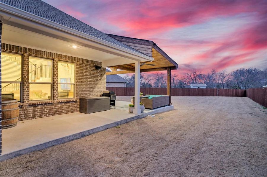 Patio terrace at dusk with outdoor furniture, a patio area, a fenced backyard, and a grill