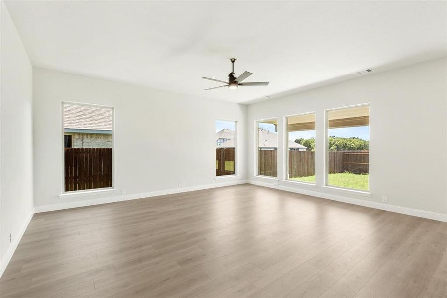 Expansive room with neutral walls, contemporary ceiling fan, and light wood-finish flooring Expansive room with neutral walls, contemporary ceiling fan, and light wood-finish flooring