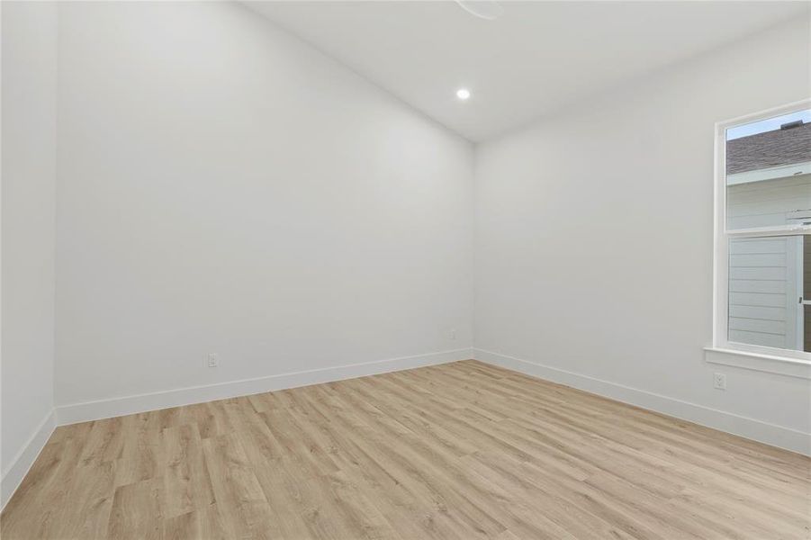 Empty room with light wood-style flooring, baseboards, lofted ceiling, and recessed lighting Empty room with light wood-style flooring, baseboards, lofted ceiling, and recessed lighting