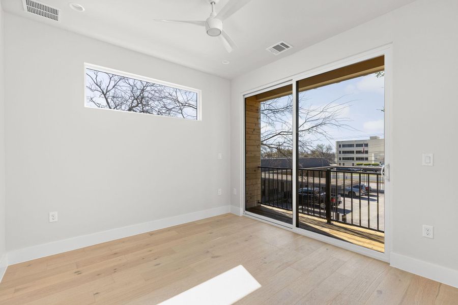 Unfurnished room with a ceiling fan, wood finished floors, visible vents, and baseboards