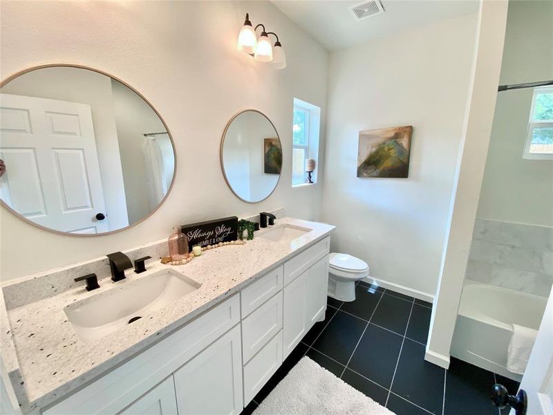 Bathroom featuring toilet, tile patterned flooring, and dual bowl vanity