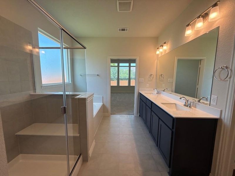 Spacious bathroom with dual vanities featuring dark cabinetry and white countertops Spacious bathroom with dual vanities featuring dark cabinetry and white countertops