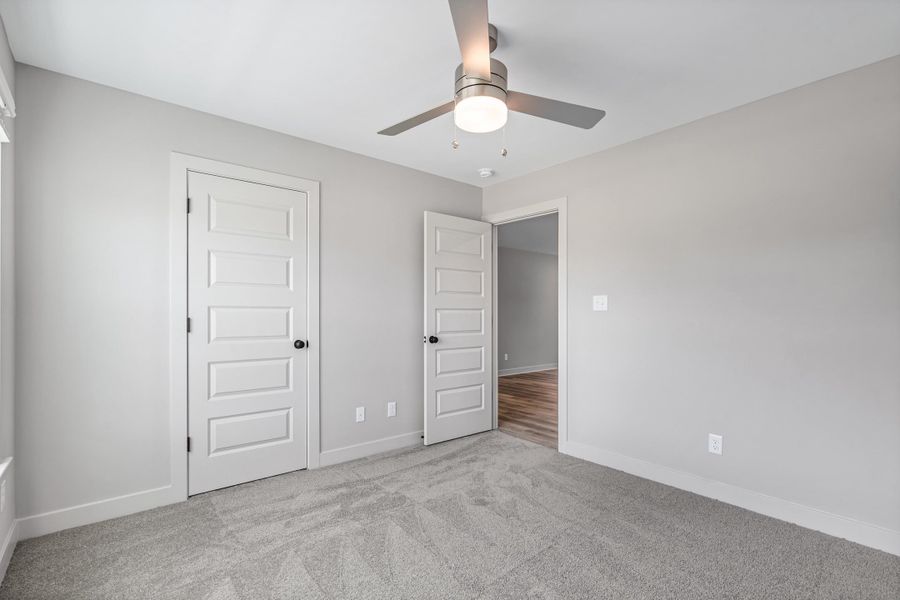Light gray wall paint, five-panel interior doors, light gray carpet flooring, ceiling fan with brushed nickel finish