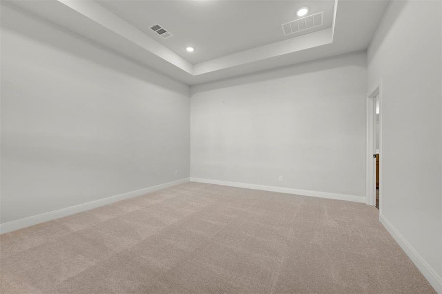 Empty room with carpet flooring, a raised ceiling, and recessed lighting