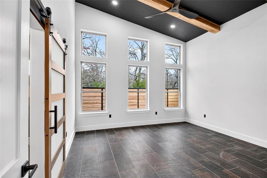 Empty room with a barn door, vaulted ceiling, recessed lighting, and ceiling fan Empty room with a barn door, vaulted ceiling, recessed lighting, and ceiling fan