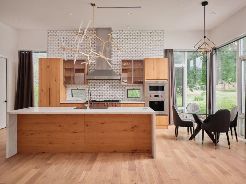 An open-concept kitchen with light wood flooring flows seamlessly into a dining area, offering direct access to the outdoors. An open-concept kitchen with light wood flooring flows seamlessly into a dining area, offering direct access to the outdoors.