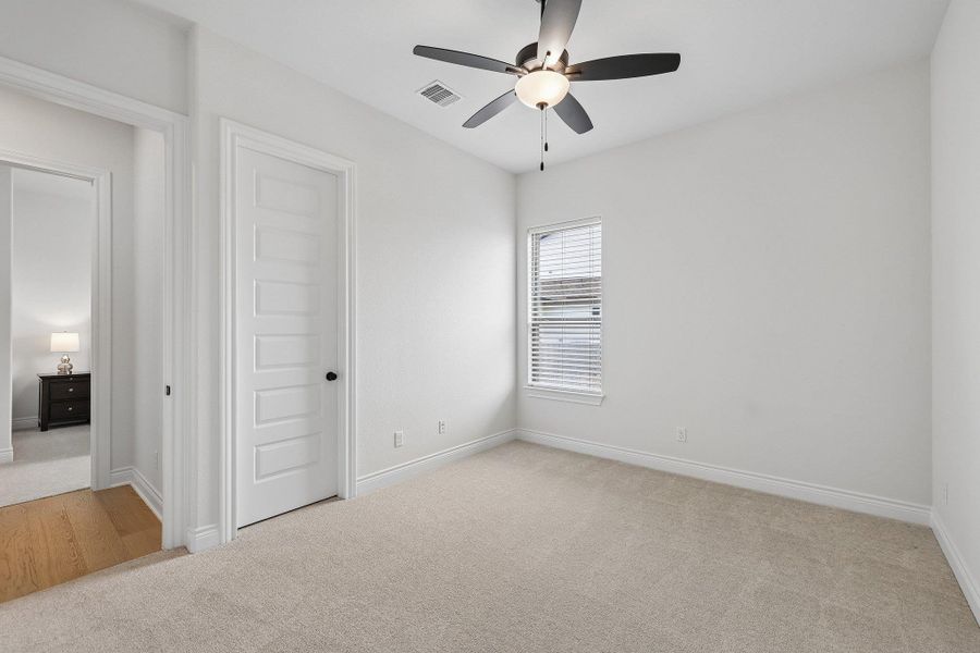 Carpeted room with a ceiling fan light fixture, white walls, and a window with blinds