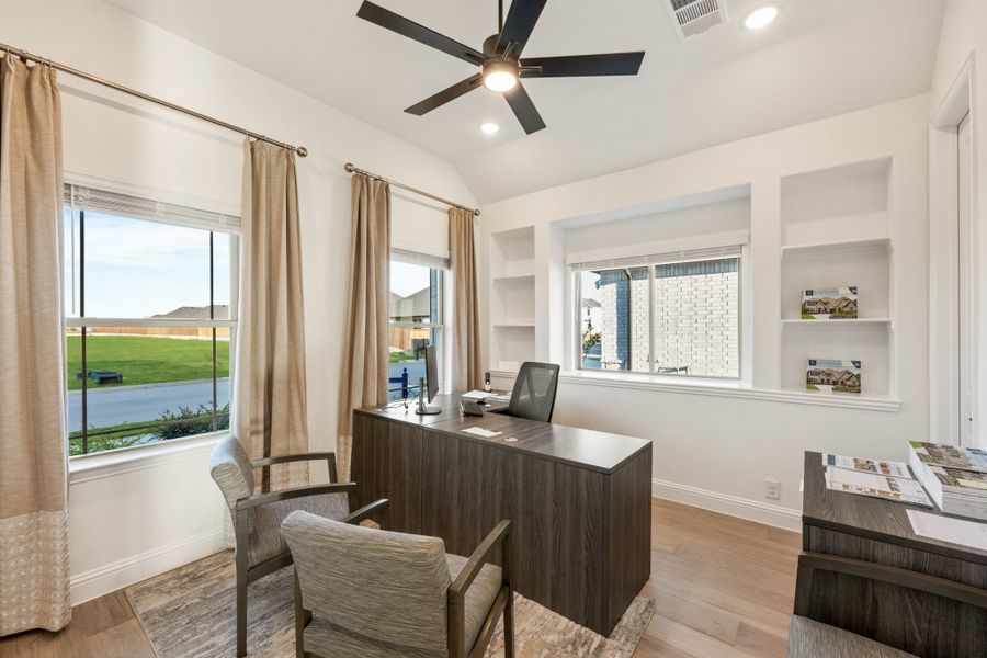Home office with dark wood desk, built-in shelves, ceiling fan, and hardwood floors