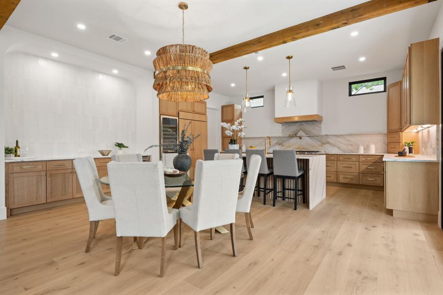 Gleaming hardwood floors and exposed wooden beams anchor this airy, open-concept culinary and dining space.