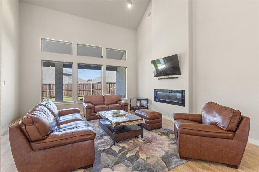 Living room featuring high vaulted ceiling, light wood-style floors, and a glass covered fireplace Living room featuring high vaulted ceiling, light wood-style floors, and a glass covered fireplace