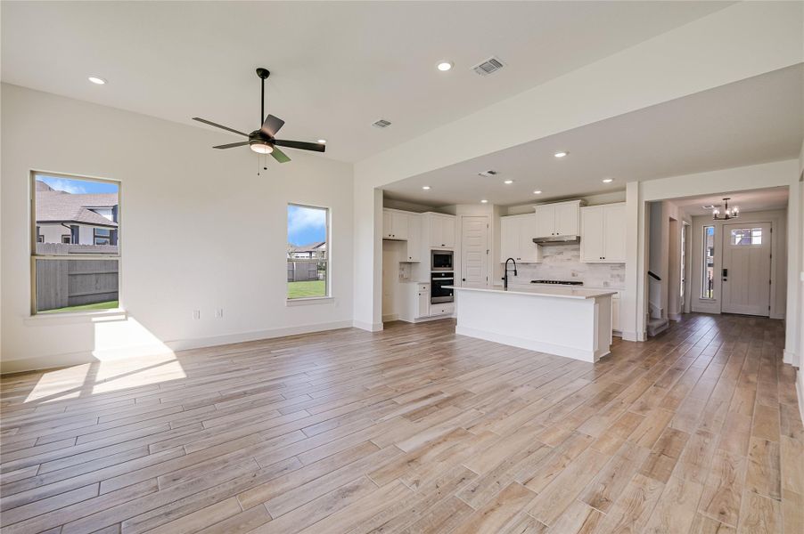 Unfurnished living room with recessed lighting, light wood finished floors, ceiling fan, and a chandelier