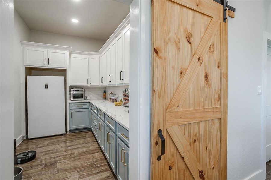 Kitchen featuring white refrigerator, a barn door, gray cabinets, and white cabinets