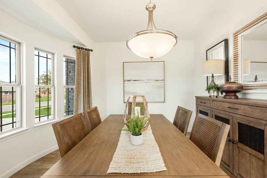 Dining room with wood table, cane-back chairs, pendant light, and wood sideboard
