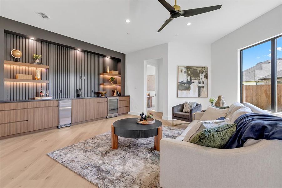 Living room with wine cooler, light wood-style flooring, ceiling fan, and recessed lighting Living room with wine cooler, light wood-style flooring, ceiling fan, and recessed lighting