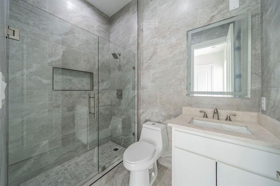 Bathroom with tile walls, a stall shower, and vanity Bathroom with tile walls, a stall shower, and vanity