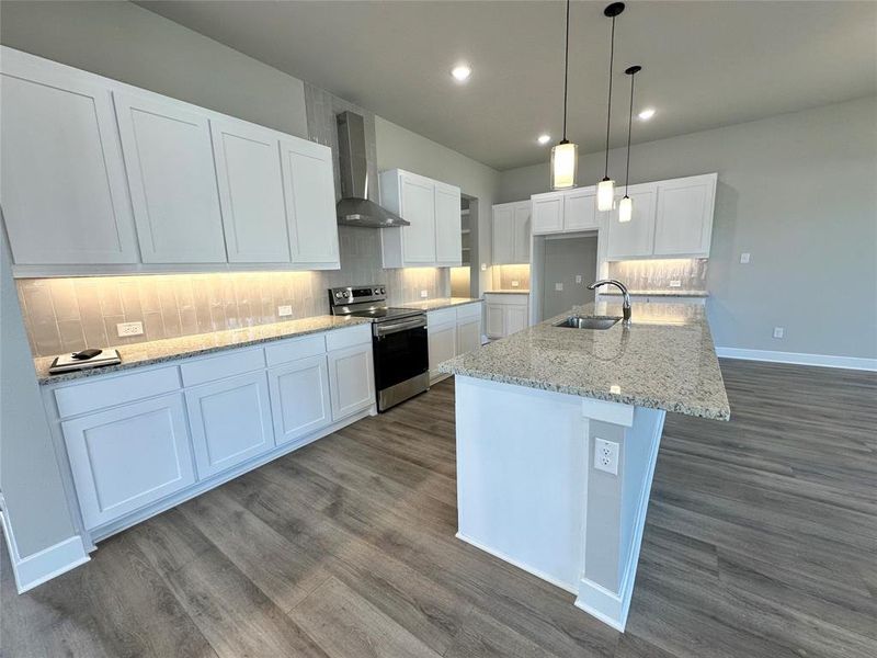 Kitchen with stainless steel electric stove, wall chimney exhaust hood, tasteful backsplash, and white cabinets