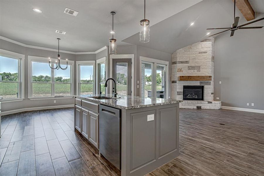 Kitchen featuring a kitchen island with sink, a fireplace, dishwasher, pendant lighting, and sink