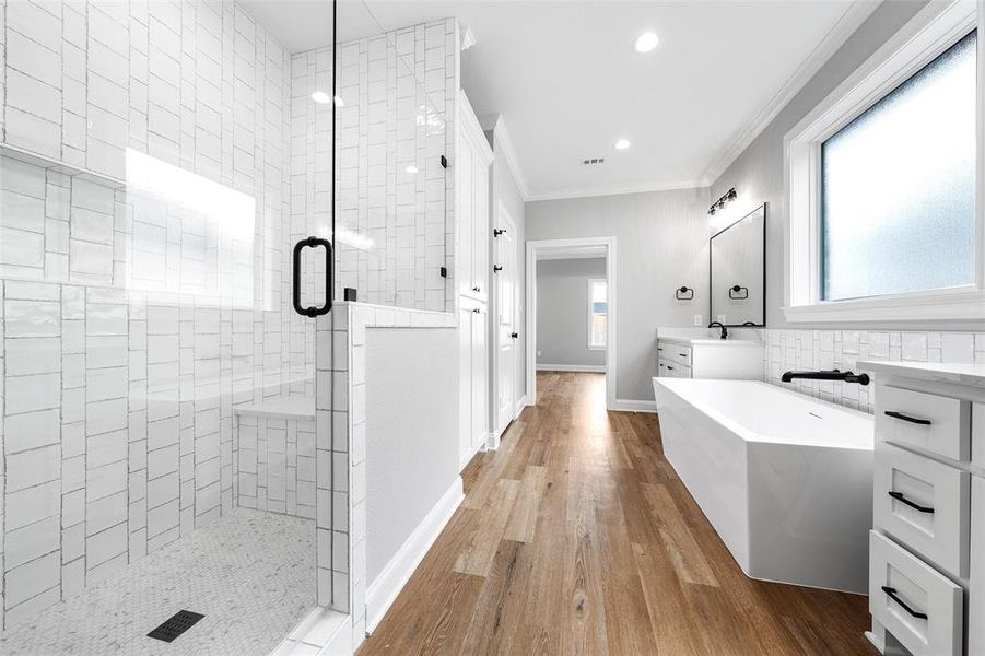Bathroom featuring a shower stall, ornamental molding, vanity, light wood-style flooring, and a freestanding bath Bathroom featuring a shower stall, ornamental molding, vanity, light wood-style flooring, and a freestanding bath