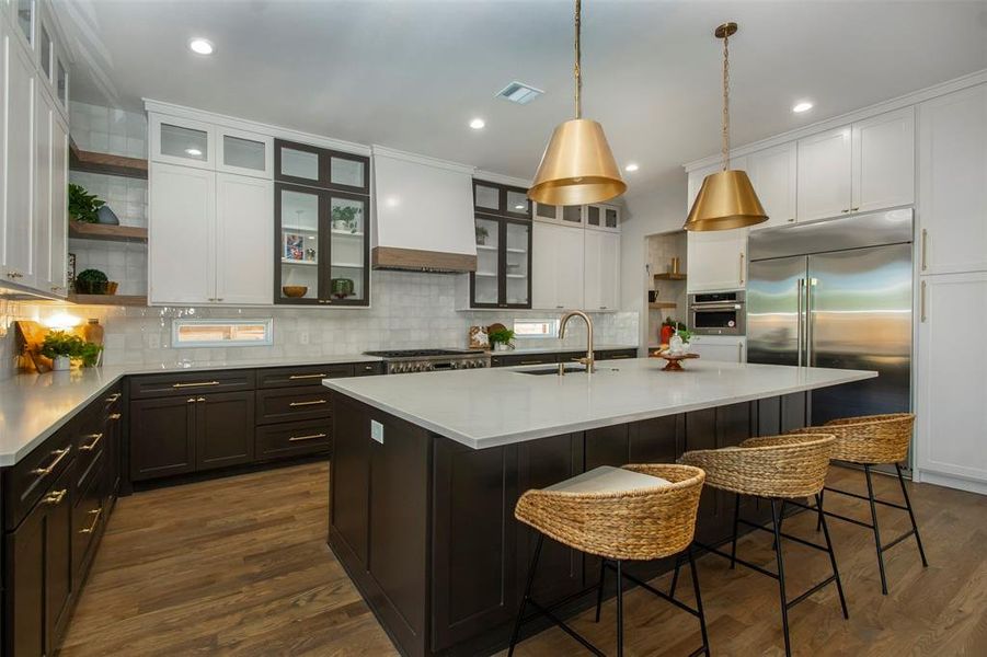 Kitchen with sink, dark hardwood / wood-style flooring, a breakfast bar area, a center island with sink, and appliances with stainless steel finishes