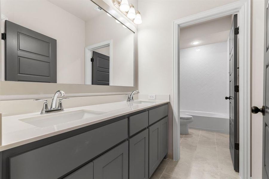 Full bathroom featuring dual vanity, toilet, shower / bathing tub combination, and tile patterned flooring