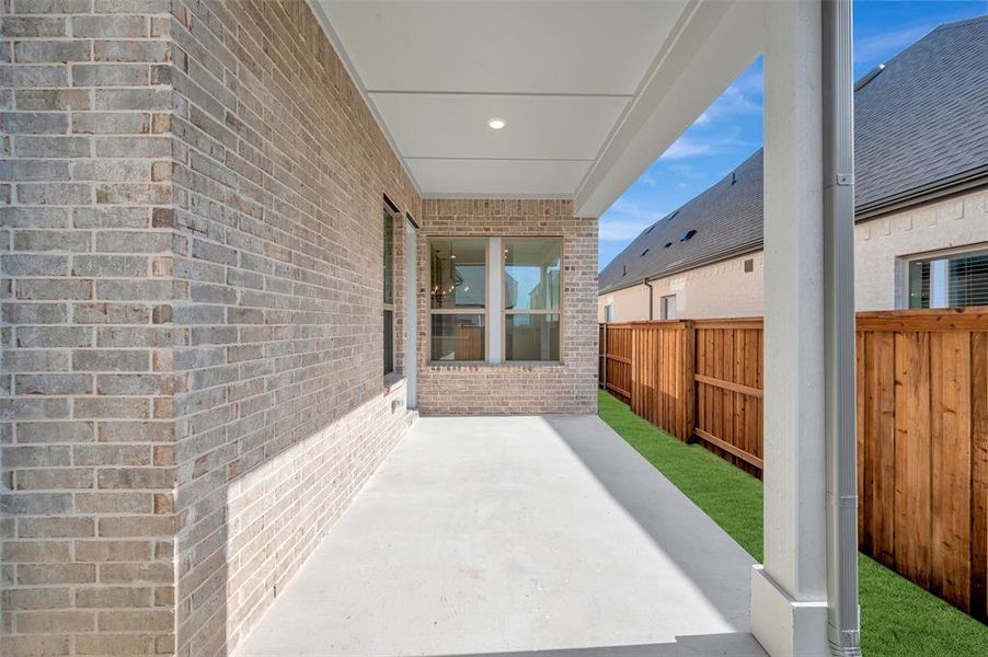 Covered patio featuring a concrete surface, overhead lighting, and a brick exterior Covered patio featuring a concrete surface, overhead lighting, and a brick exterior