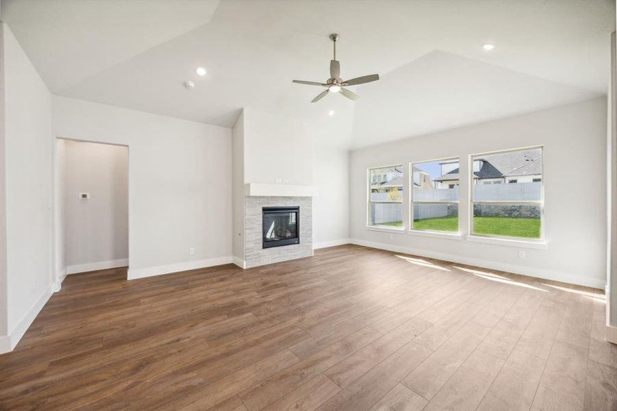 Unfurnished living room with a fireplace, hardwood / wood-style floors, high vaulted ceiling, and ceiling fan