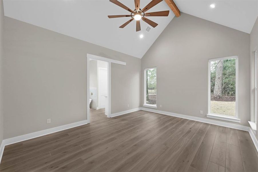 A view into your primary bedroom with en-suite bathroom and vaulted ceilings with a cedar beam.