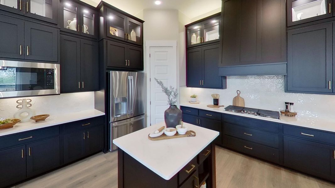 Kitchen featuring glass fronted cabinets, stainless steel appliances, a kitchen island, and light wood finished floors