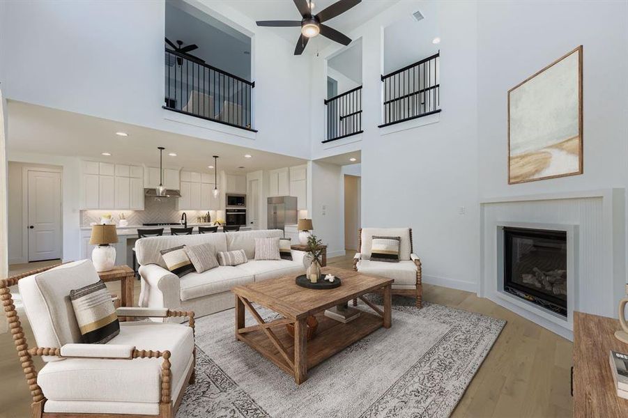 Virtually staged photo - Living area featuring a glass covered fireplace, light wood-style floors, a ceiling fan, and recessed lighting