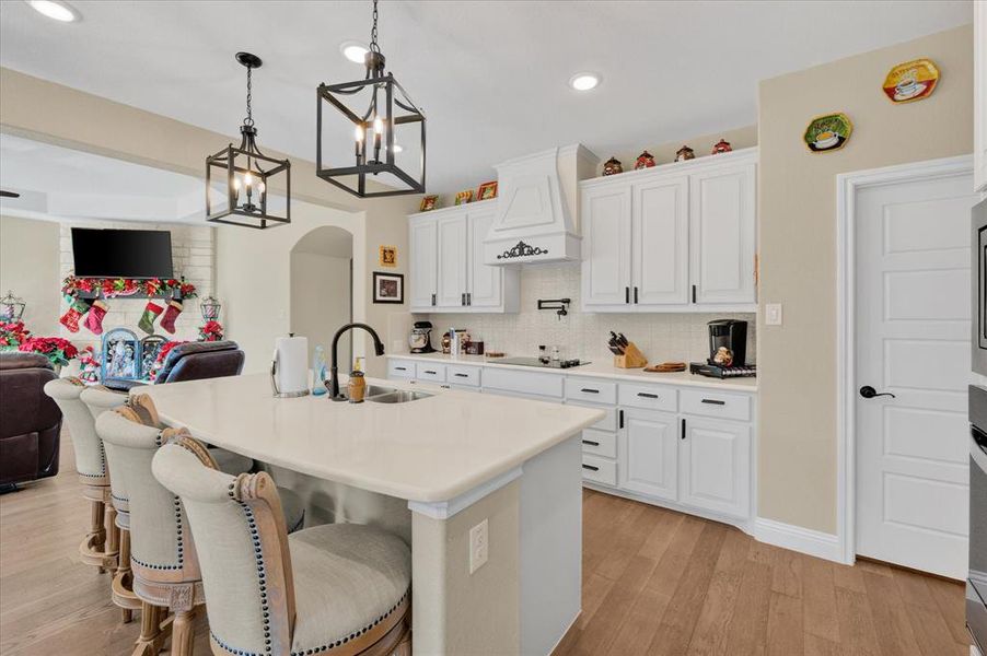 Kitchen featuring arched walkways, a kitchen bar, white cabinetry, decorative light fixtures, and recessed lighting Kitchen featuring arched walkways, a kitchen bar, white cabinetry, decorative light fixtures, and recessed lighting