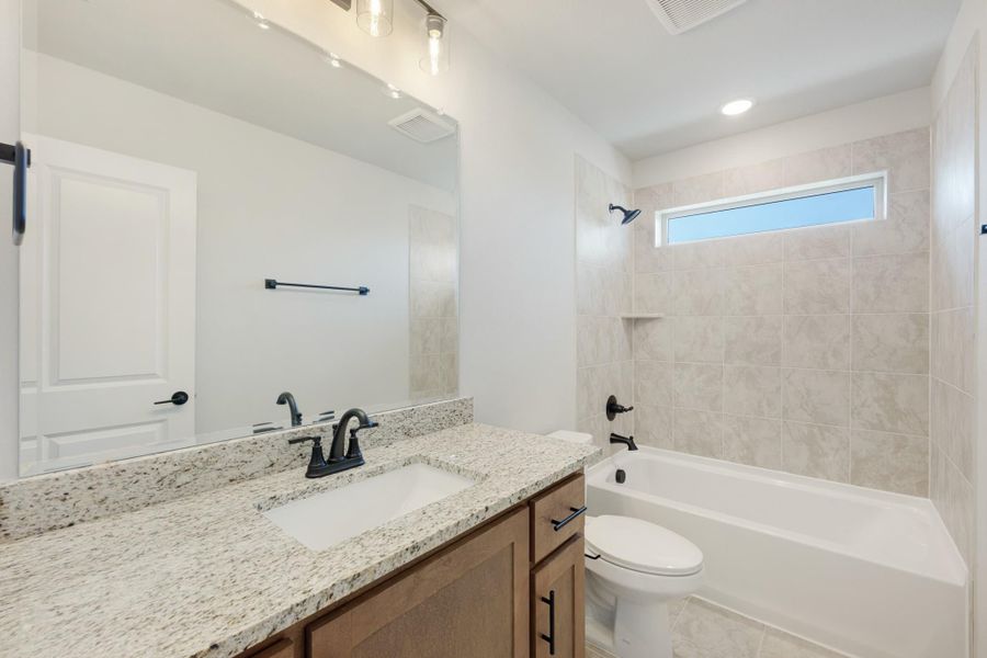 Bathroom with granite vanity, single sink, tub-shower combo with tile surround, and black fixtures Bathroom with granite vanity, single sink, tub-shower combo with tile surround, and black fixtures
