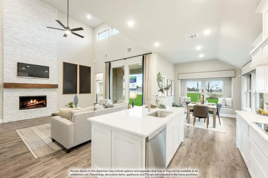 Open-concept living area with kitchen island, stone fireplace, vaulted ceiling, and hardwood floors