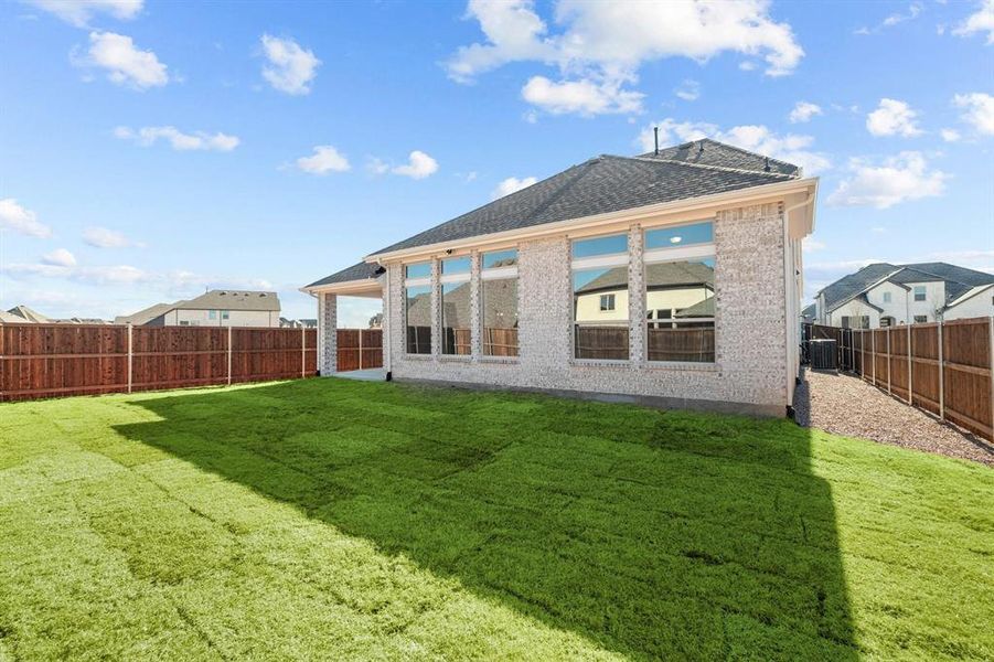 Expansive backyard featuring new sod, privacy fencing, a covered patio, and a light brick exterior with multiple large windows Expansive backyard featuring new sod, privacy fencing, a covered patio, and a light brick exterior with multiple large windows